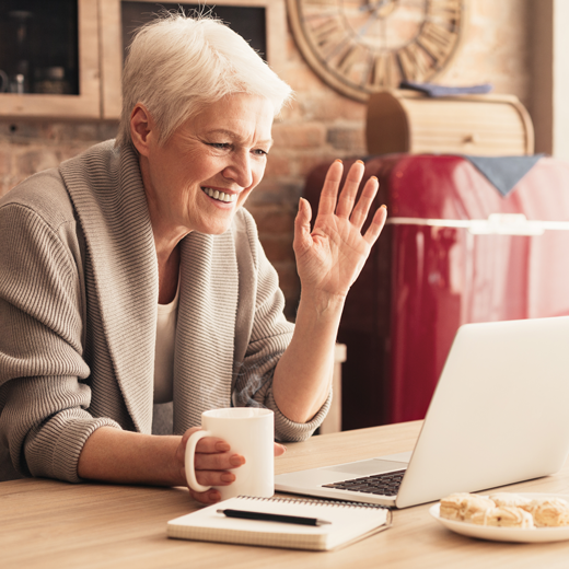 smiling lady wearing dentures waving on video call